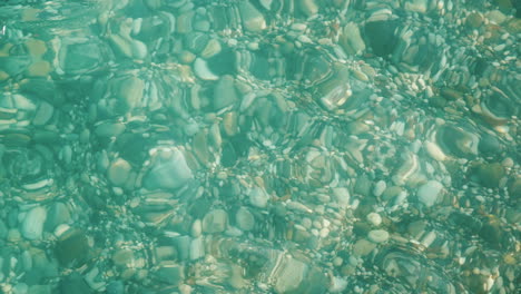 through the crystal clear sea water you can see a variety of sea stones on the sea coast