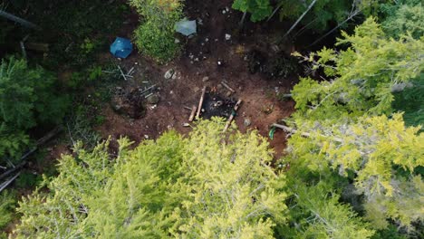 tiro ascendente de un dron de una caravana cocinando sobre un fuego en el bosque con tiendas de campaña en el fondo