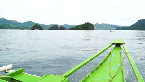cabalgando frente a un pequeño bote de pasajeros verde en coron palawan