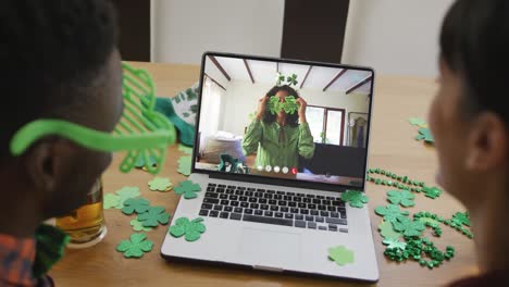 mujer afroamericana sonriente que usa artículos en forma de trébol en una videollamada en una computadora portátil