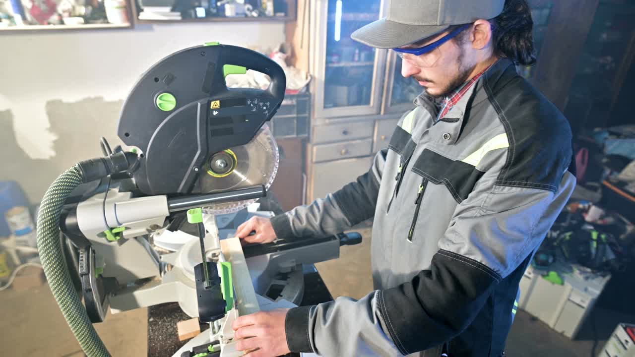 A young carpenter installs a wooden work piece in a circular sawing machine.