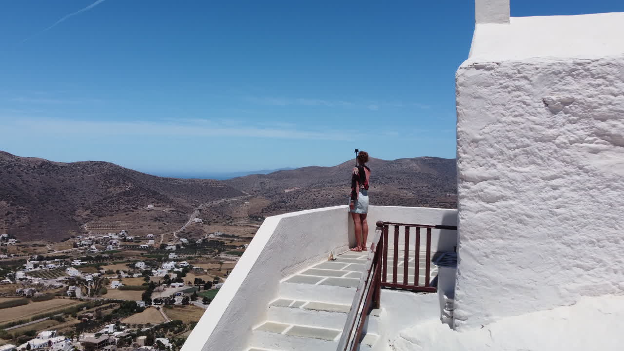 mujer haciendo video de vacaciones, pueblo de chora, isla de ios, grecia