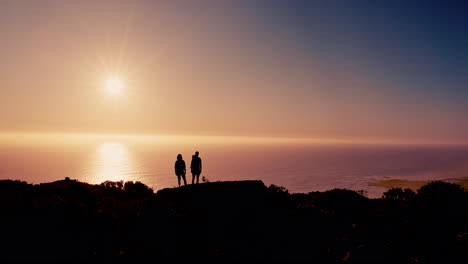 couple silhouetted against sunset over ocean