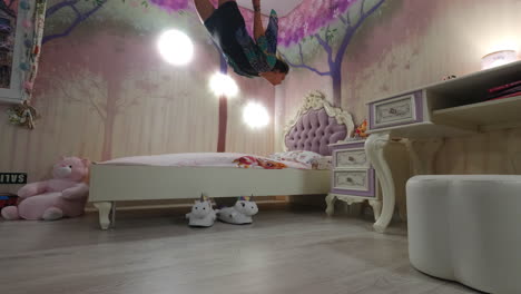 toma fantástica de una niña flotando sobre la cama en un dormitorio blanco y rosa