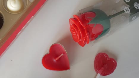 bright red rose candle, heart-shaped candles, and a heart lollipop for valentine's day