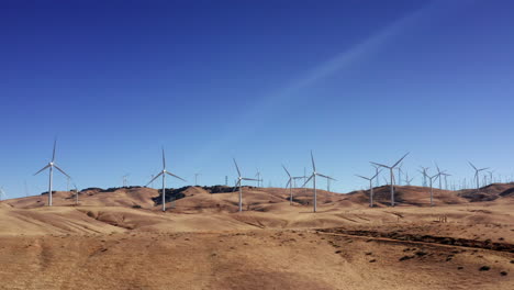 wind turbines generate clean and renewable energy on the hills of tehachapi in southern california - slow motion aerial view