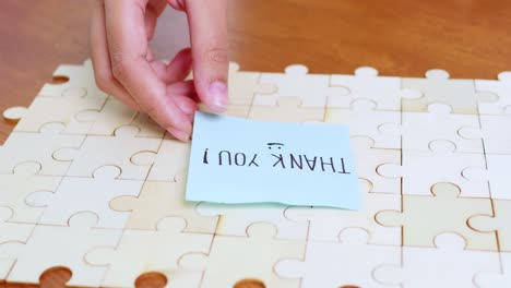 a hand places a thank-you note a completed puzzle symbolizing appreciation and joy