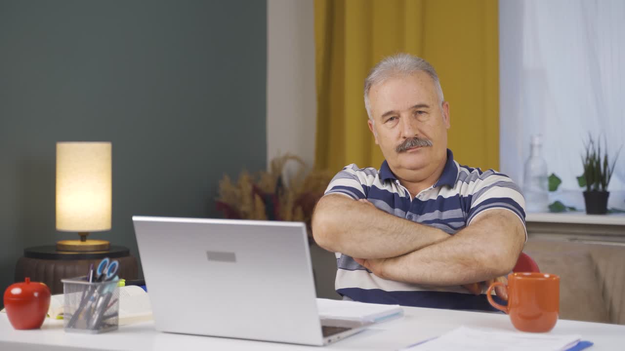 Home office worker old man makes a trust sign to the camera.