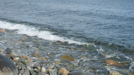 onde marine che schizzano sulla spiaggia rocciosa in norvegia - angolo alto