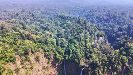 drone approaches the majestic twin streams of tad fane waterfall plunging 120 meters into a jungle gorge on the bolaven plateau near pakse, laos, surrounded by dense tropical rainforest