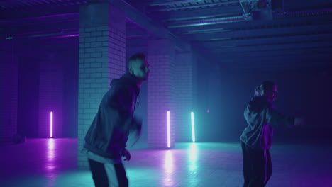 Two-Professional-skill-dancers-woman-and-man-enjoying-hip-hop-moves-performing-freestyle-dance-together-in-an-abandoned-building.-Caucasian-band-make-modern-freestyle-dance-indoors.