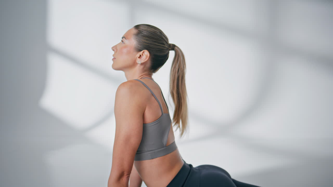 Serene yoga woman training at white studio closeup. Relaxed woman stretching
