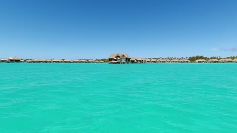 from boat in lagoon, over water villa cabanas in french polynesia