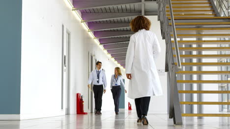 two doctors in discussion as they walk along hospital corridor