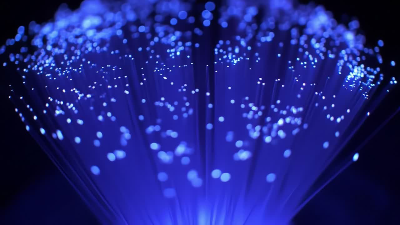 Glowing blue fibers radiating light in a dark setting, creating a mesmerizing display of luminous particles and intricate patterns that evoke a sense of wonder.