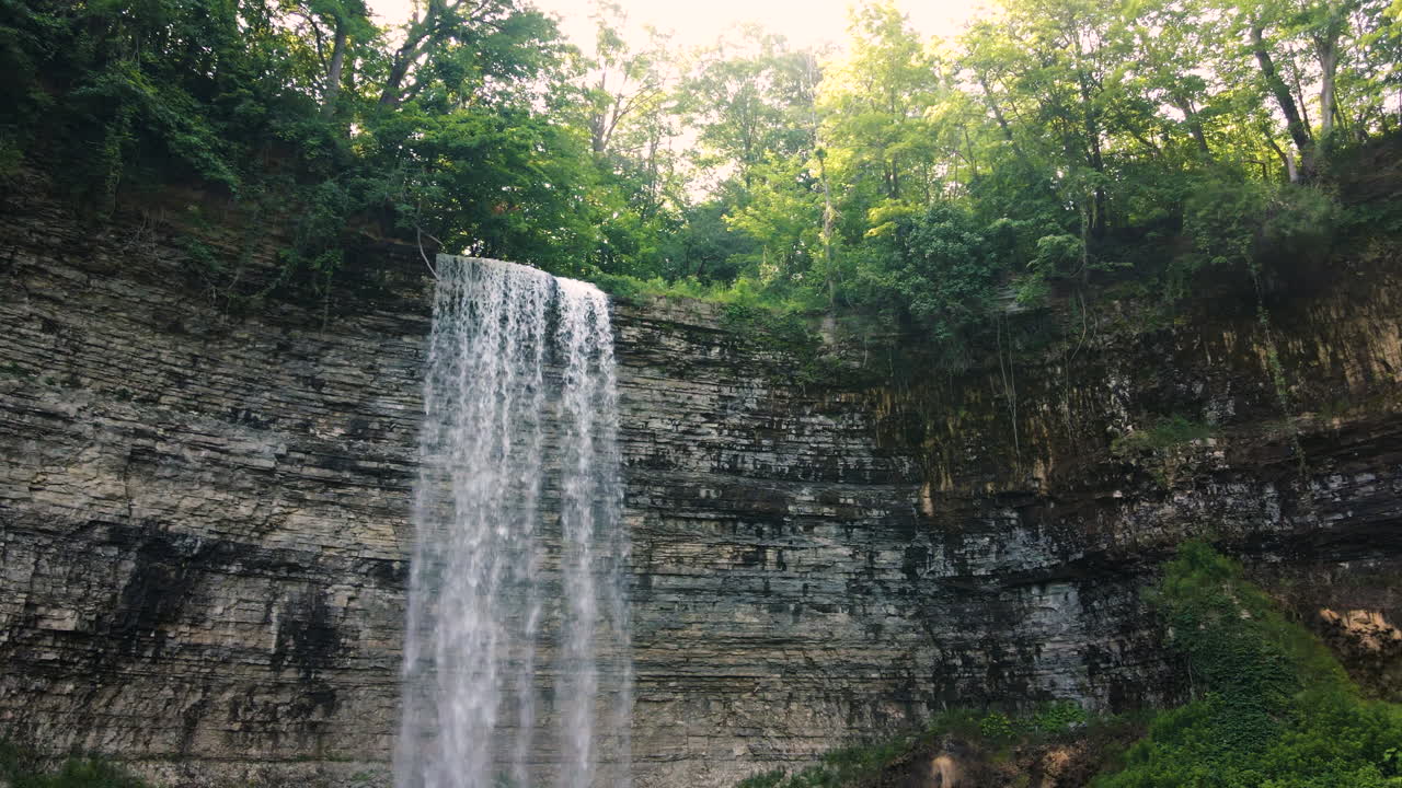 la luz del sol brillando a través de los árboles por encima de la cascada de cinta de tew falls ontario canadá