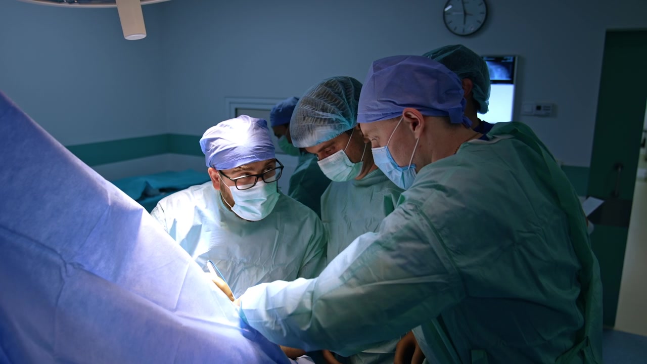 Squadra di tre chirurghi che lavorano a un intervento di chirurgia traumatologica. I medici comunicano e collaborano durante l'operazione.