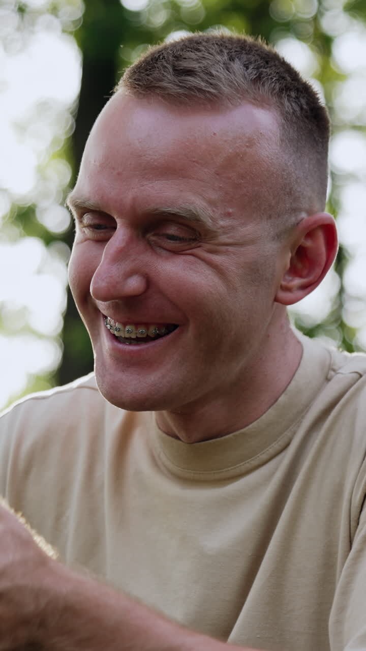Smiling Caucasian man looks at his smartphone. Businessman receives a call and talk cheerfully looking at camera. Close up. Vertical video