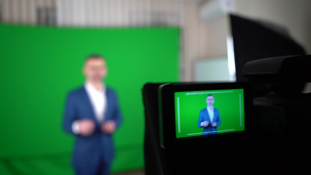 블로거가 녹색 배경에서 비디오를 녹음하고 있습니다. 캠코더는 블로거를 녹음하고 있다.