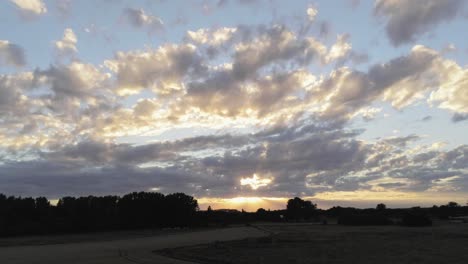 Gloriosa-Puesta-De-Sol-Y-Paisaje-De-Cielo-Nublado-Sobre-El-Prado-Verde-Y-Los-Campos-De-Maíz-En-El-Campo