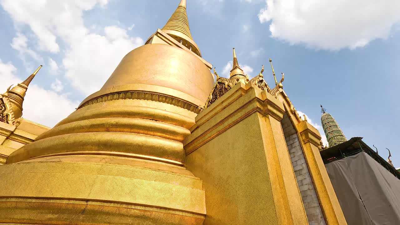 una vista dinámica de la pagoda dorada en wat phra kaew, mostrando su intrincada arquitectura bajo la luz del día en bangkok, tailandia