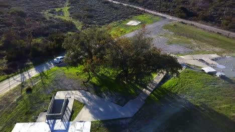 Aerial-of-car-driving-down-a-dirt-driveway-and-turning-onto-a-dirt-road