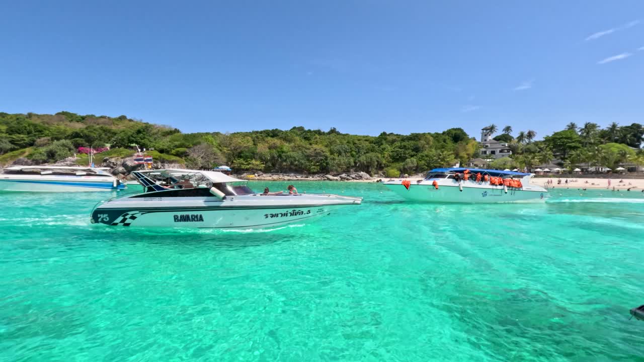 Speedboat glides over turquoise water toward lush beach, midday sun, smooth camera pan