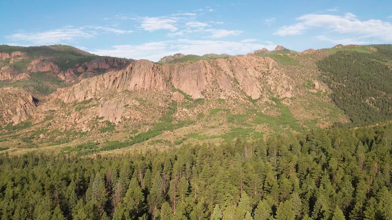 A panning drone flight over a remote mountain forest with wilderness area and rocky cliffs in the distance. Filmed in the Pike National Forest of Colorado