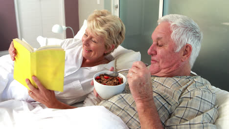 Pareja-Mayor-Leyendo-Un-Libro-Y-Comiendo-Cereal