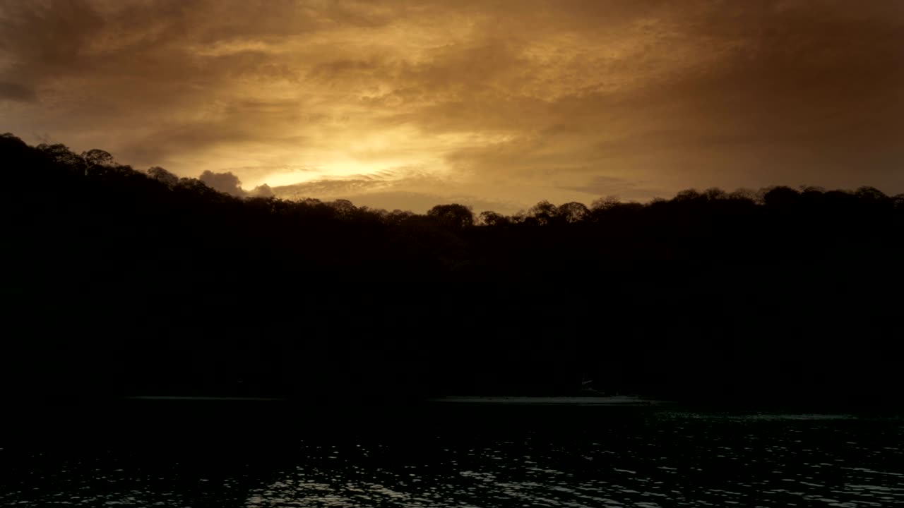 Gorgeous view from the ocean of island back lit by a sunset sky.