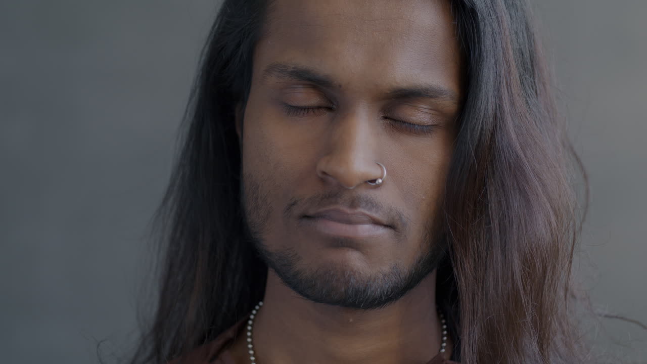 Close-up portrait of a man with long hair and nose ring