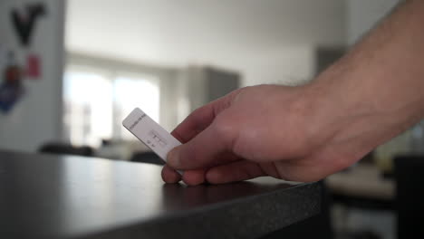 closeup-of-hand-holding-a-covid-test-in-the-living-room-showing-positive