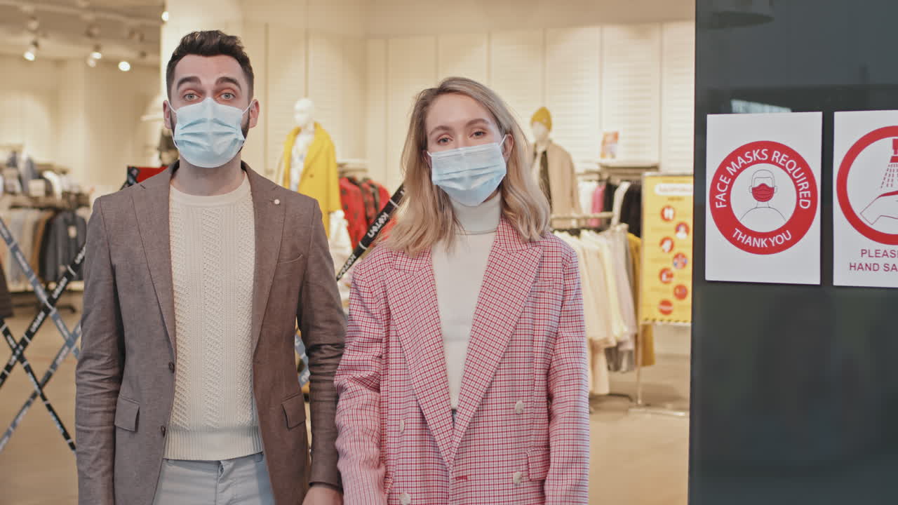 Portrait Of Couple Putting On Face Masks At Shopping Centre
