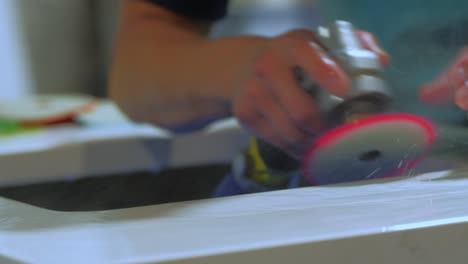 close up of worker polishing edge of granite kitchen countertop - quartz -rock with a blue polisher with water in a warehouse