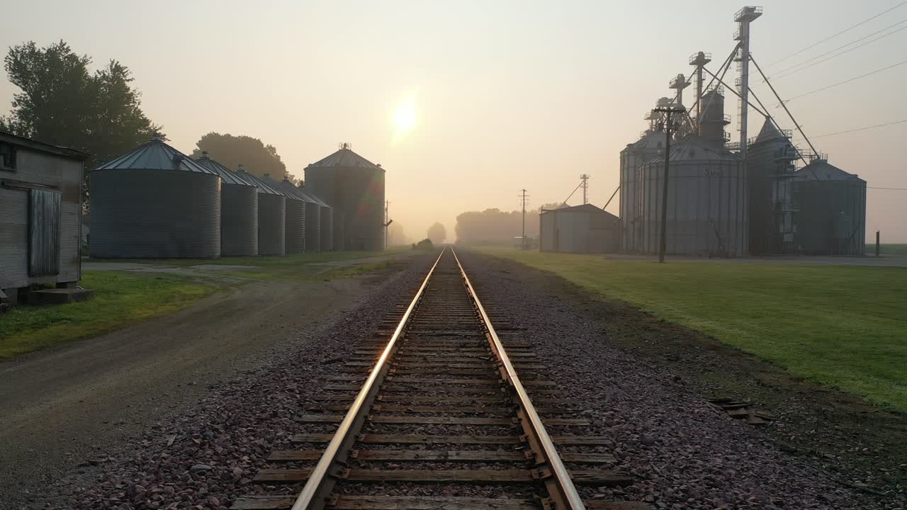 amanecer sobre un ferrocarril rural con silos de grano
