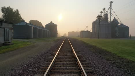 sunrise over a rural railroad with grain silos