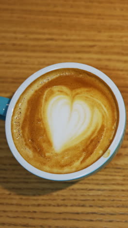 cup of coffee close up. coffee cup with art foam on wooden table