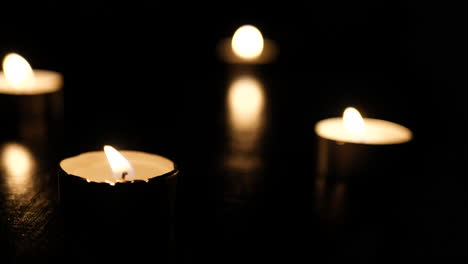 tea light candles burning on fire in slow motion in a dark room with heavy bokeh for background and banners