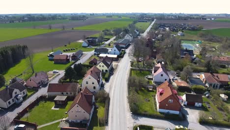 aerial shot of a small countryside town called löderup in south sweden skåne with a bird flying and a car driving on the road