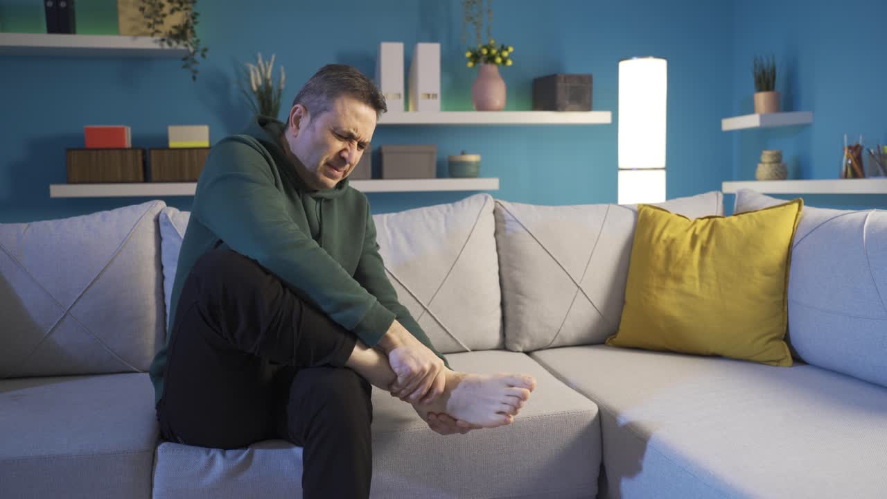 발에 심한 통증이 있는 성숙한 남자가 발목을 문지르고 있습니다. 피로 증상.