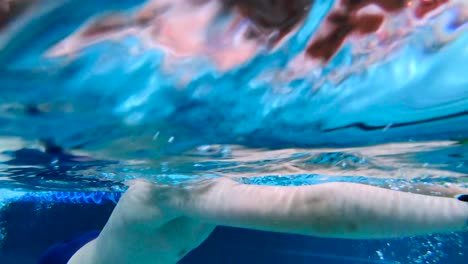 niño activo nadando en la piscina cubierta bajo el agua usando gafas