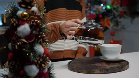 Close-up-of-woman-pouring-cup-of-tea-from-kettle-at-home