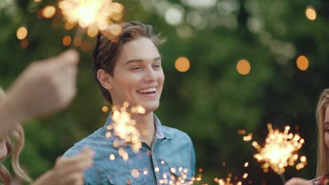 amigos felices con chispas divirtiéndose al aire libre