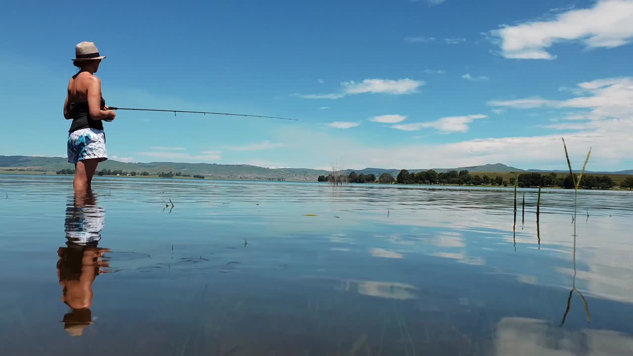 девушка стоит в чистом голубом озере и ловит рыбу в солнечный день