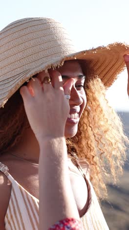 smiling woman with curly hair and straw hat in summer sun