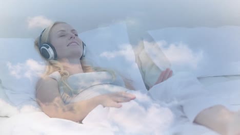 Animación-De-Nubes-Moviéndose-Sobre-Una-Mujer-Caucásica-Con-Los-Ojos-Cerrados-Escuchando-Música-Mientras-Está-Acostada-En-La-Cama