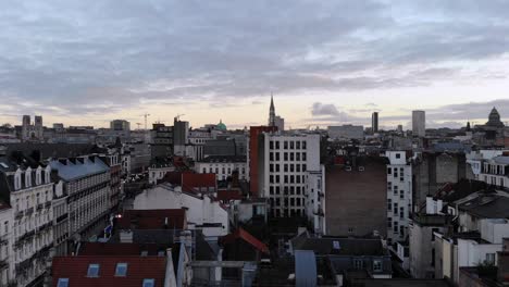 aerial side close flight towards buildings of brussels city on cloudy day, belgium