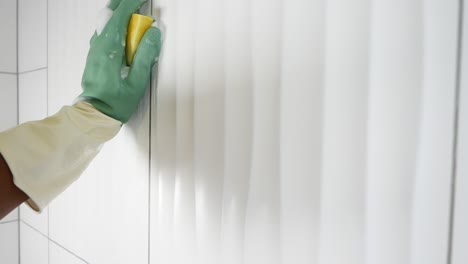 cleaning bathroom tiles with gloves and sponge