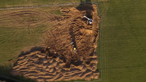 Sandy-construction-site-in-its-beginning-state-with-two-excavators-and-one-person-approaching-them