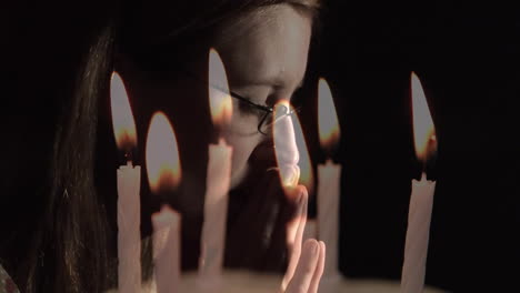 video compuesto de velas encendidas contra el primer plano de una mujer caucásica orando